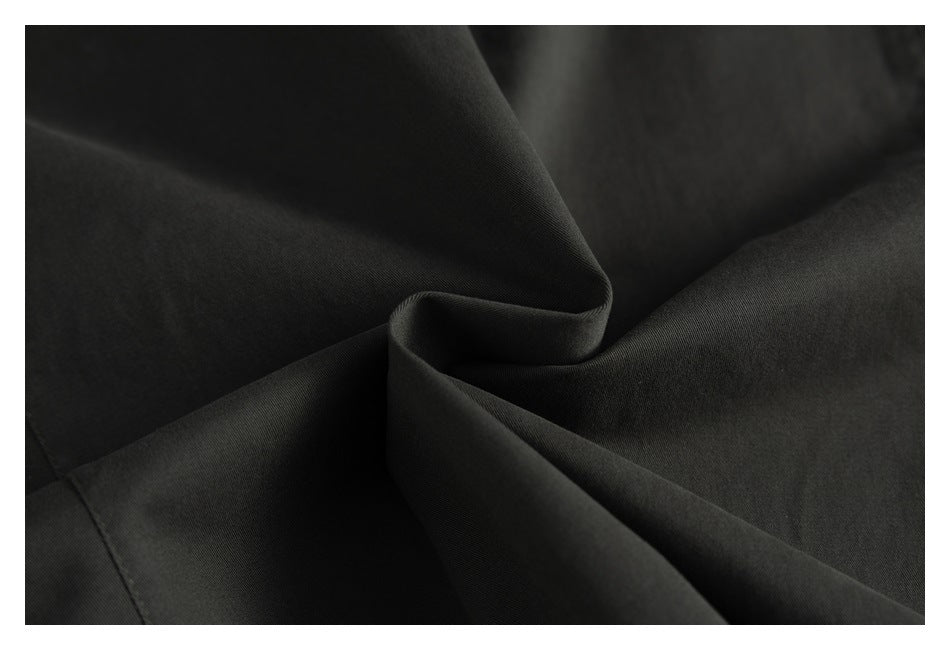 Close-up of dark charcoal garment fabric folded to show its surface and drape.