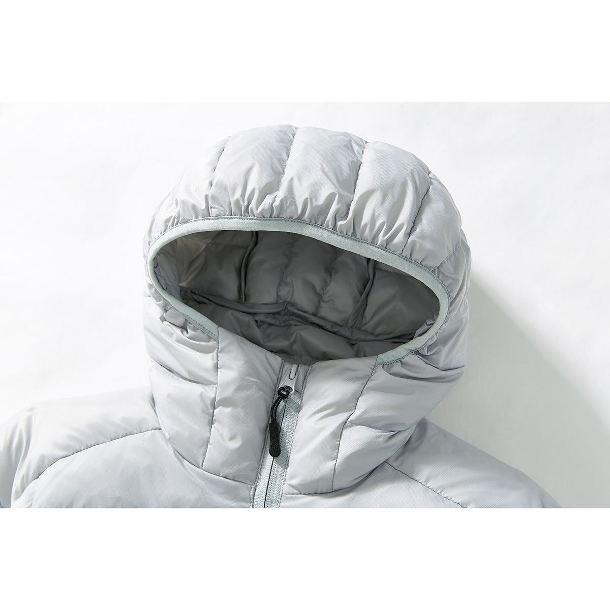 Close-up of a light gray quilted jacket’s padded hood, dark lining, and front zipper.