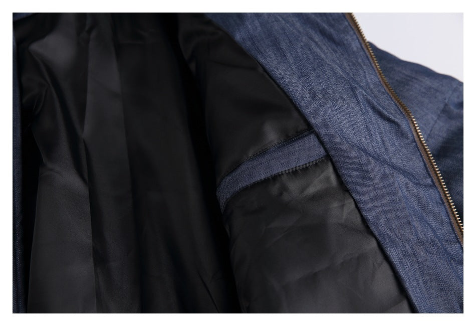Close-up of a blue denim jacket opened to show its black lining and brass-colored zipper.
