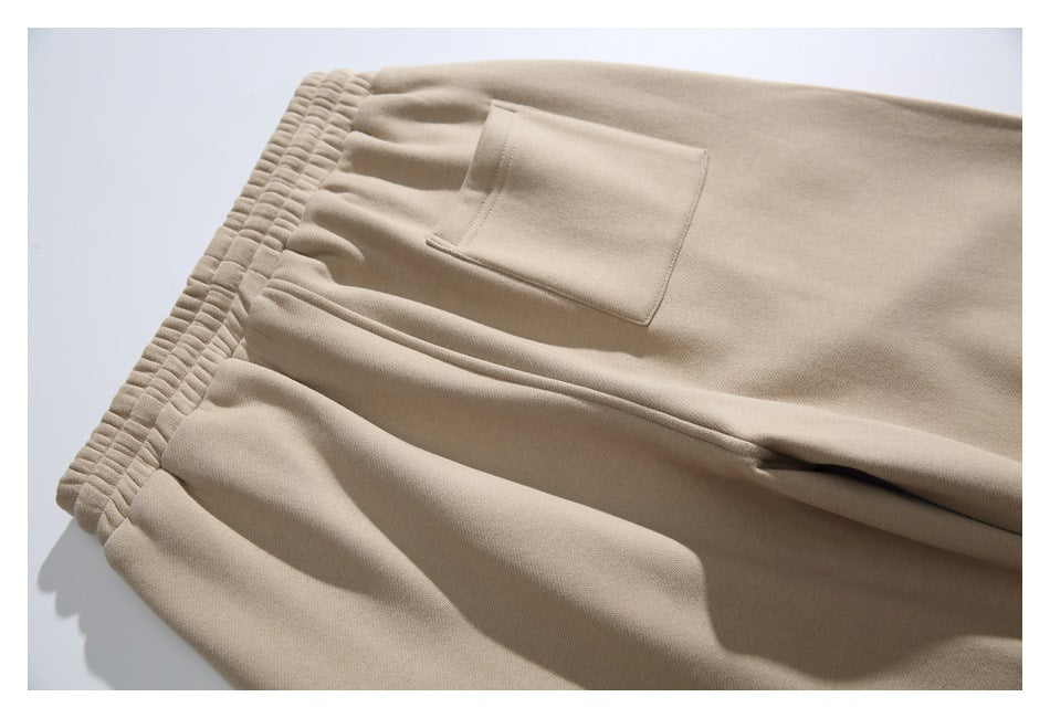 Close-up of beige pants laid flat, showing the elastic waistband and a rectangular pocket.