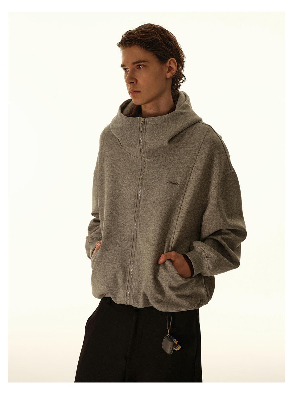 Model wearing a gray zip-up hoodie with an oversized hood, ribbed cuffs and small chest embroidery.