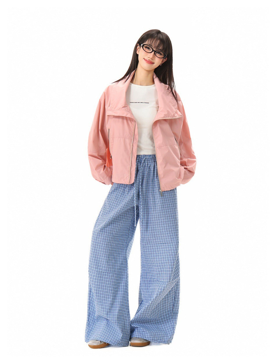 Model wearing pink cropped zip jacket with open collar over a white tee and blue gingham wide-leg pants