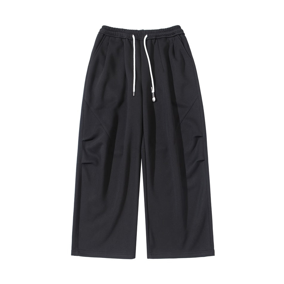 Black wide-leg drawstring pants with elastic waist, front pleats and diagonal thigh seams, flat front view