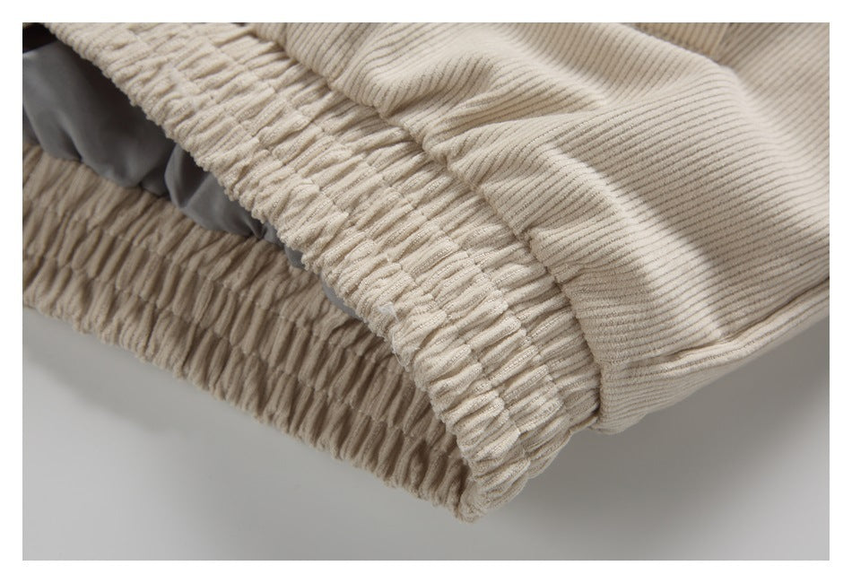 Close-up of a cream ribbed garment edge with gathered elastic stitching and gray lining.