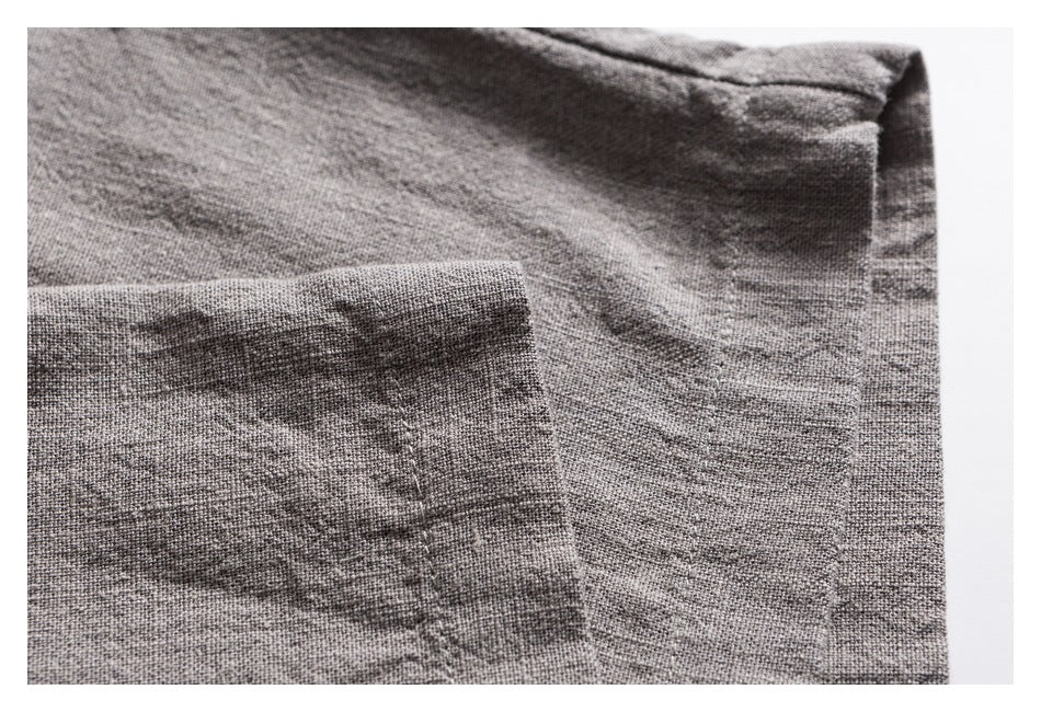 Close-up of gray textured garment fabric with a stitched pocket and seam.