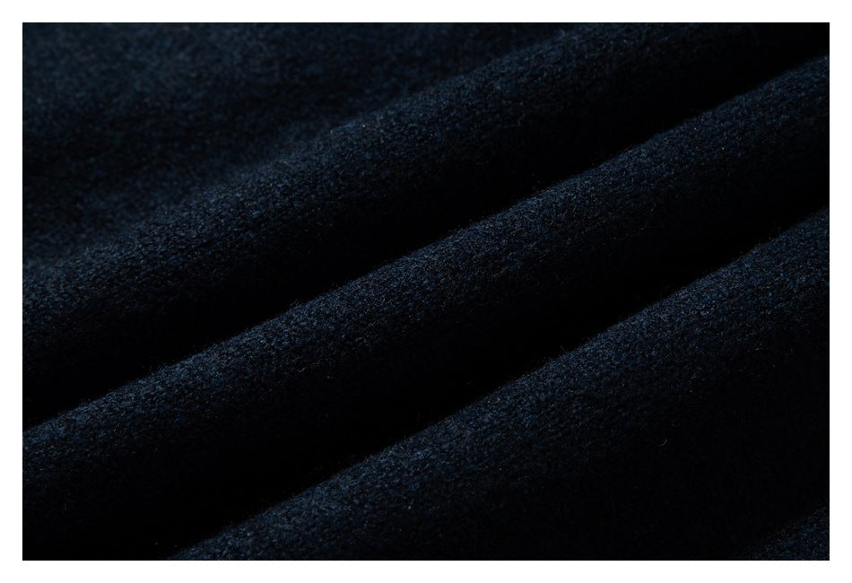 Extreme close-up of the dark navy sweater’s textured knit in soft folds.