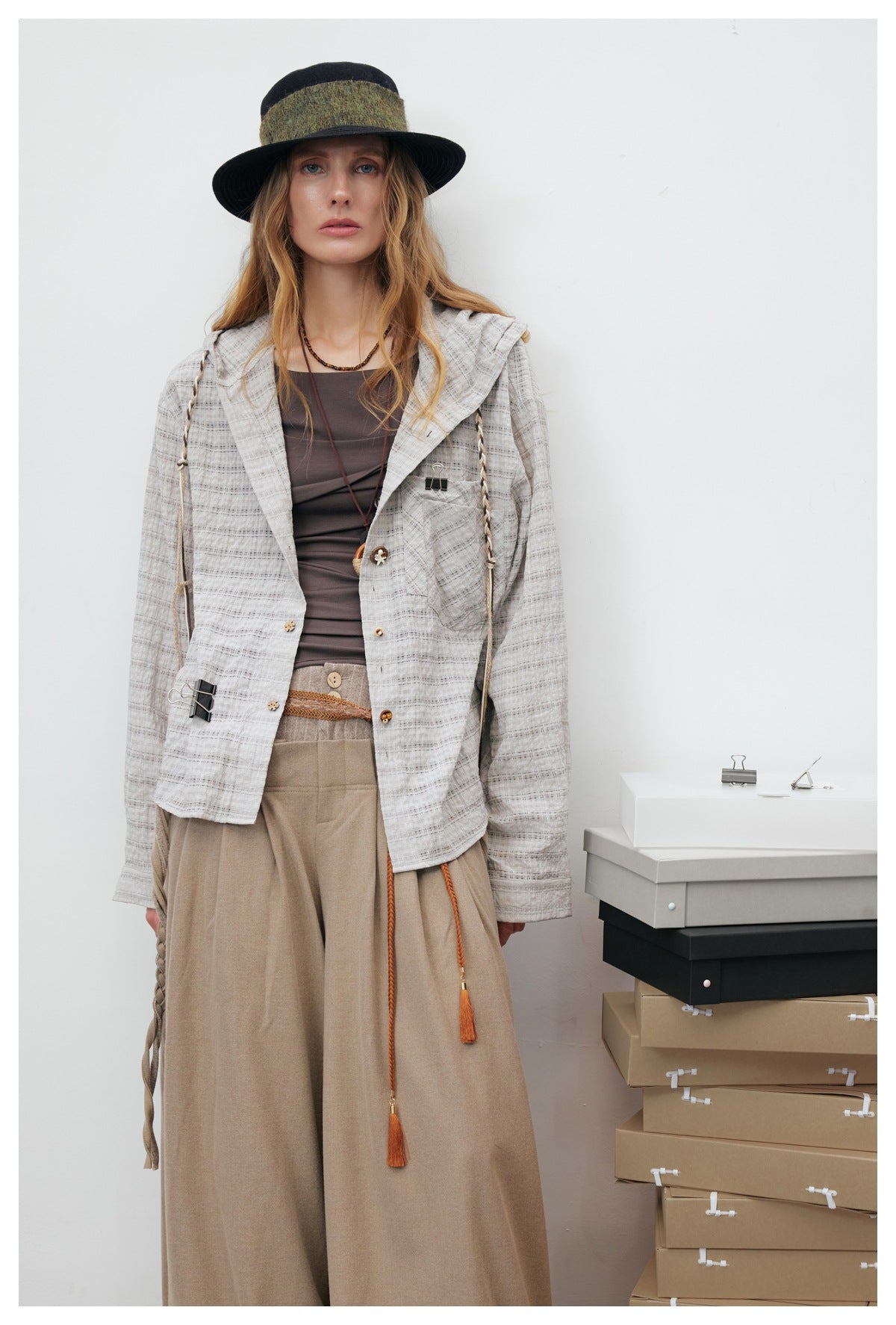 Close-up of a model in the gray plaid hooded shirt jacket with braided drawstrings, chest pocket, and mixed buttons