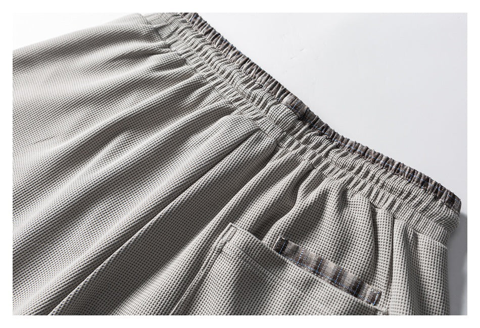 Close-up of the gray shorts' elastic waistband and a pocket with plaid trim.