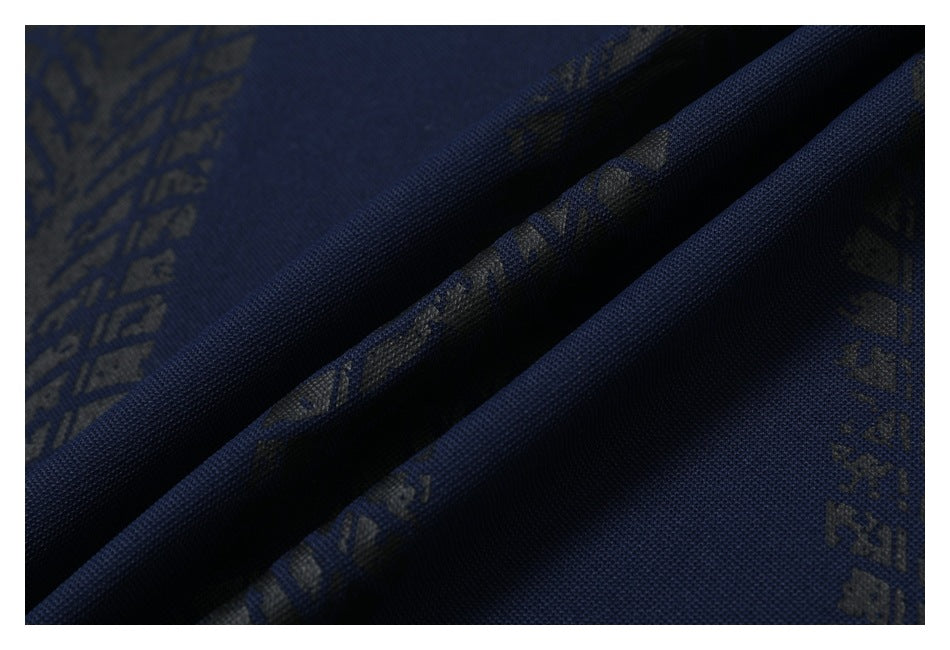 Close-up of navy fabric with dark abstract printed motifs, shown in deep diagonal folds.