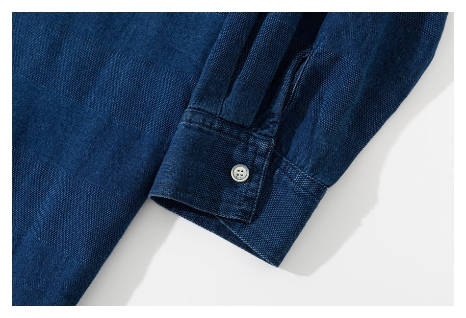 Close-up of a dark blue textured garment cuff with a light-colored button and stitched seams.
