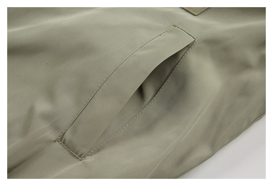 Close-up of a slanted welt pocket on olive-gray fabric.