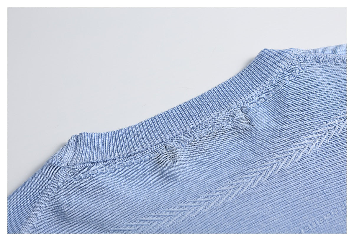 Close-up of a light blue knit sweater neckline and shoulder with ribbed trim and textured stitching.