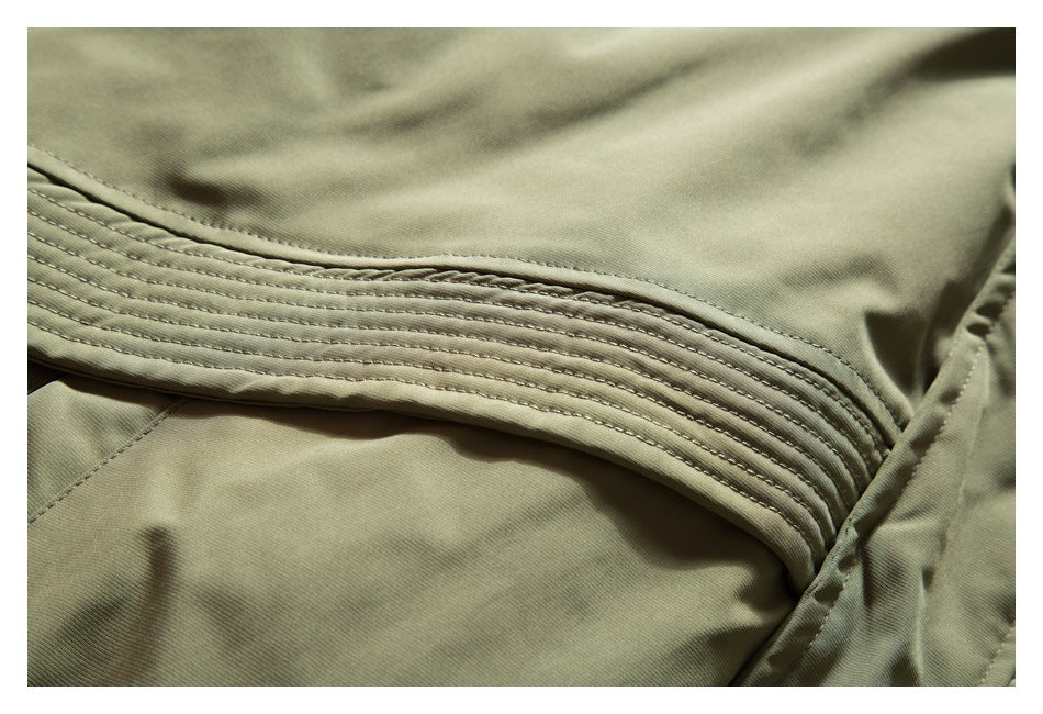 Close-up of olive-khaki garment fabric with a curved panel of parallel rows of stitching.