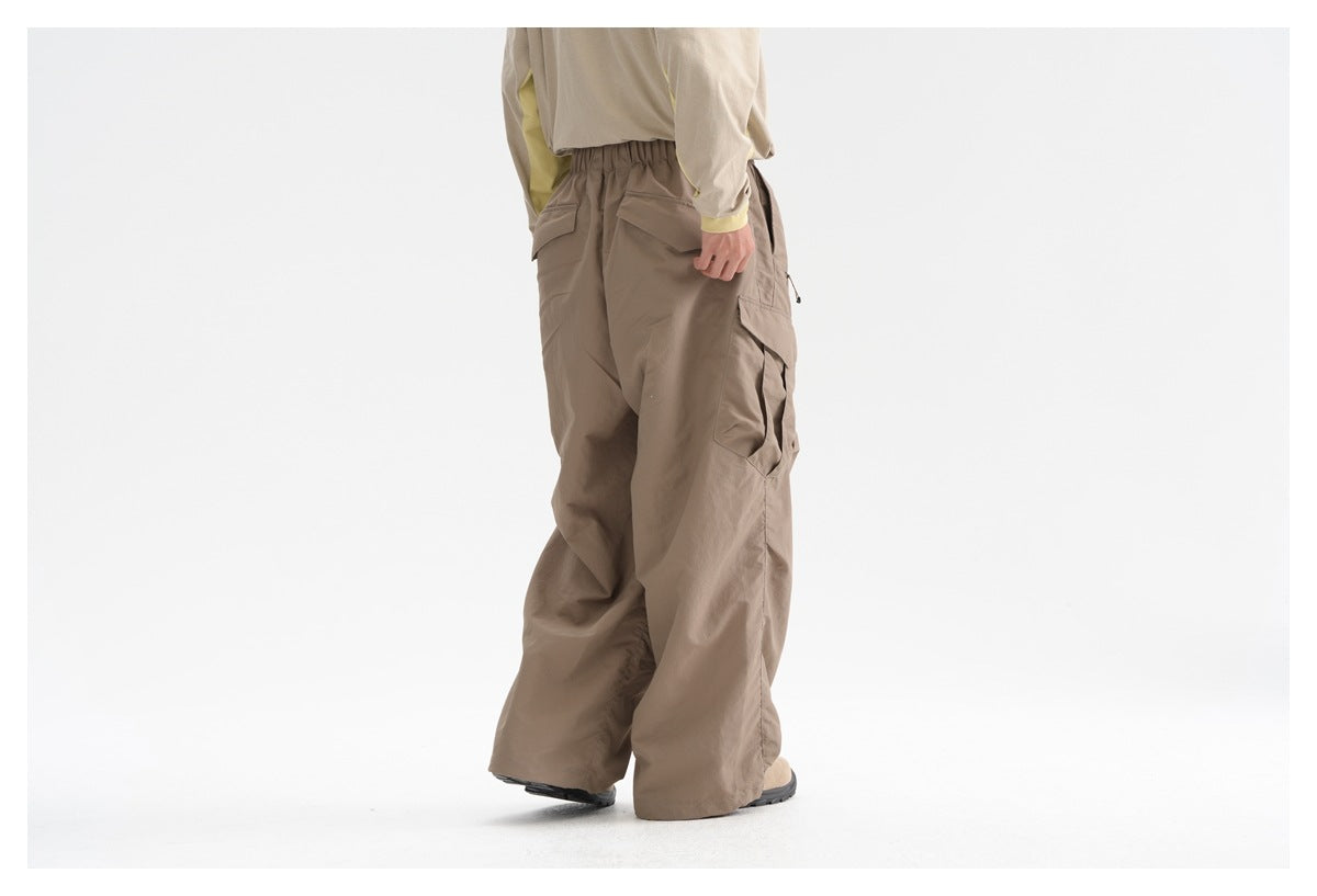 Rear view of a model wearing loose taupe cargo pants with back pockets and large side cargo pockets.