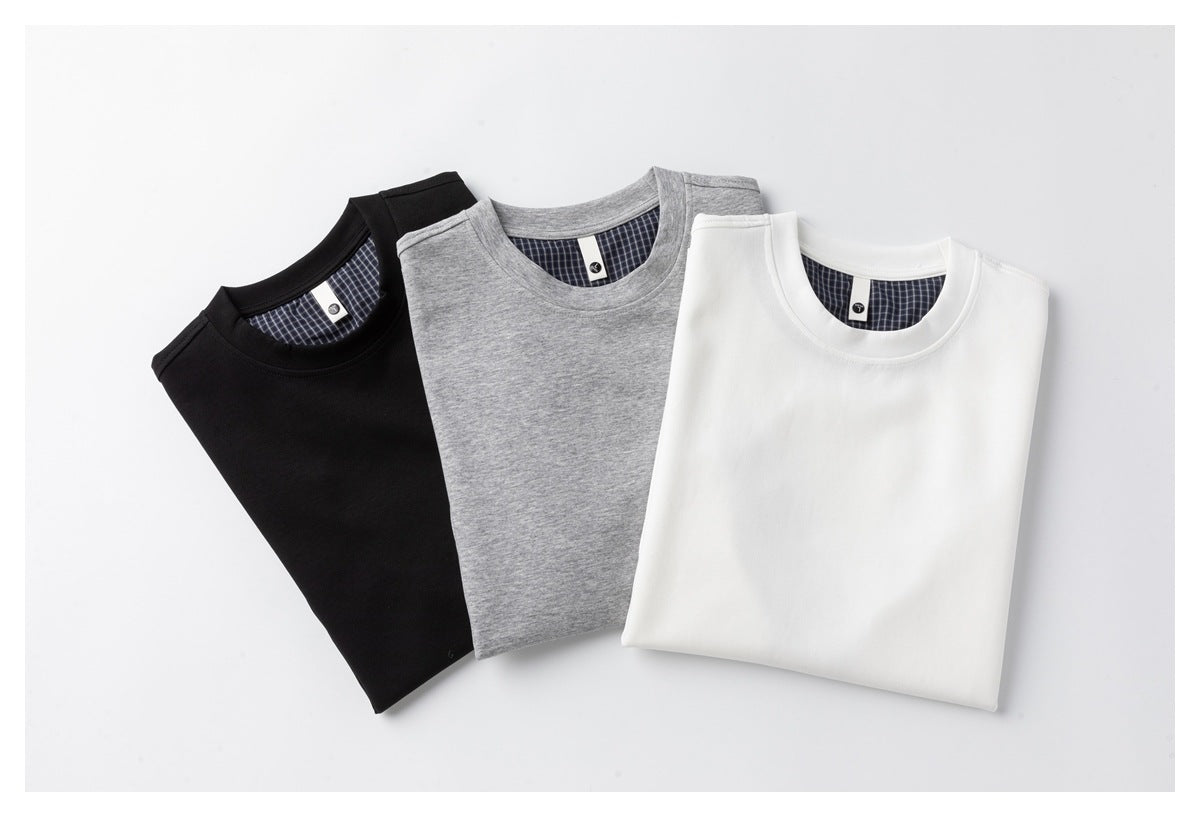 Folded black, heather gray and white T-shirts showing navy micro-check fabric at the inner back neckline