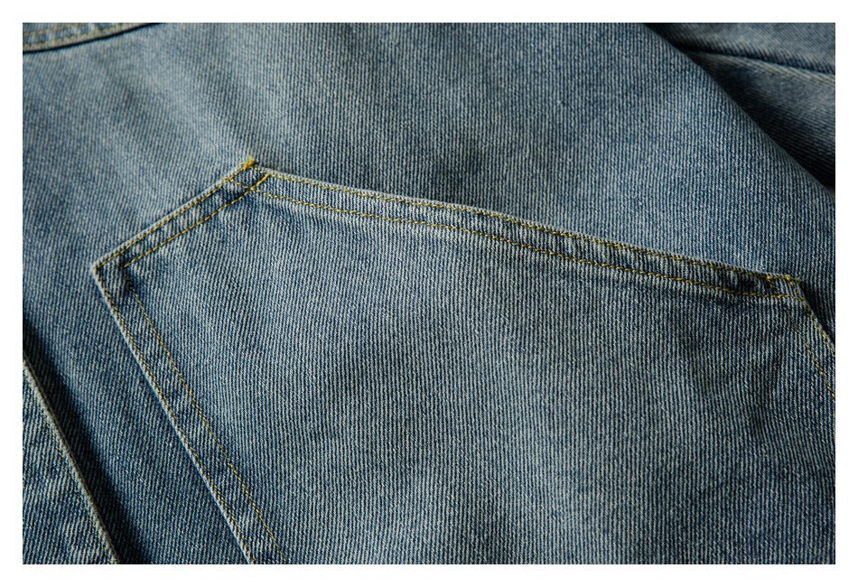 Close-up of a blue denim jacket patch pocket with double rows of yellow stitching.