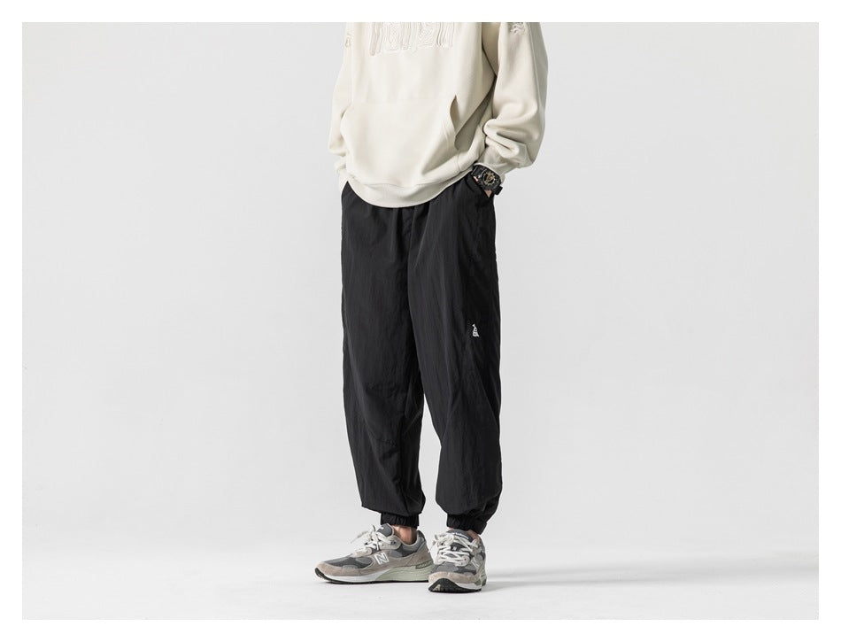 Model wearing black loose-fit jogger pants with elastic cuffs, shown from the front.