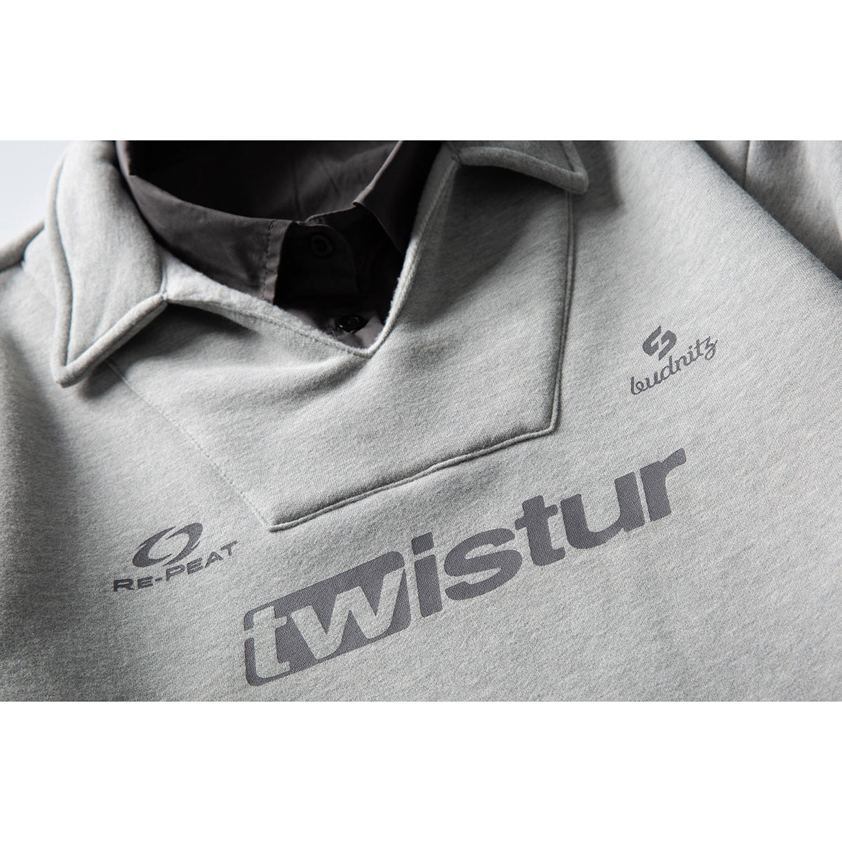 Close-up of a light gray sweatshirt chest with dark printed logos and lettering.