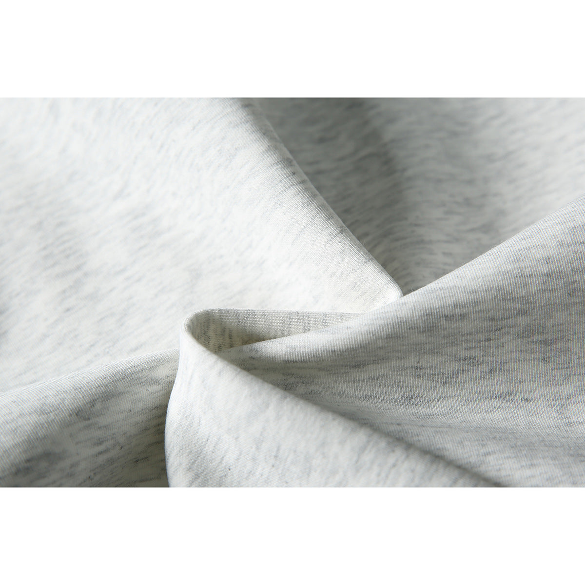 Close-up of light gray heather sweatshirt fabric and a folded garment edge.