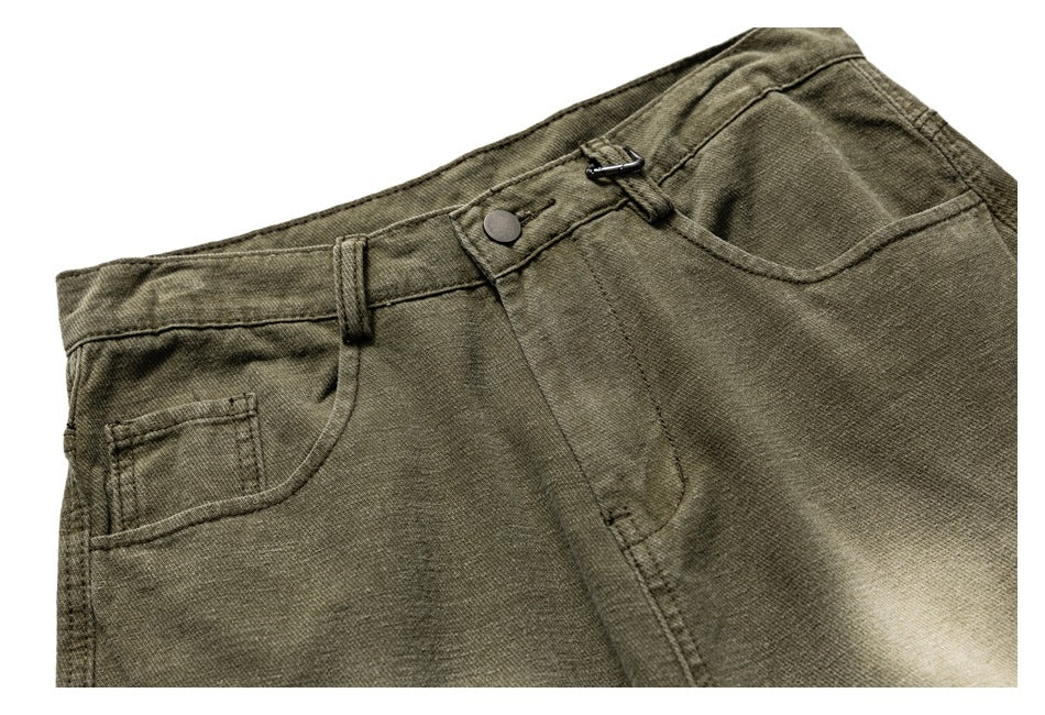 Close-up of olive trousers at the front waist, with button closure, belt loops, and pockets.