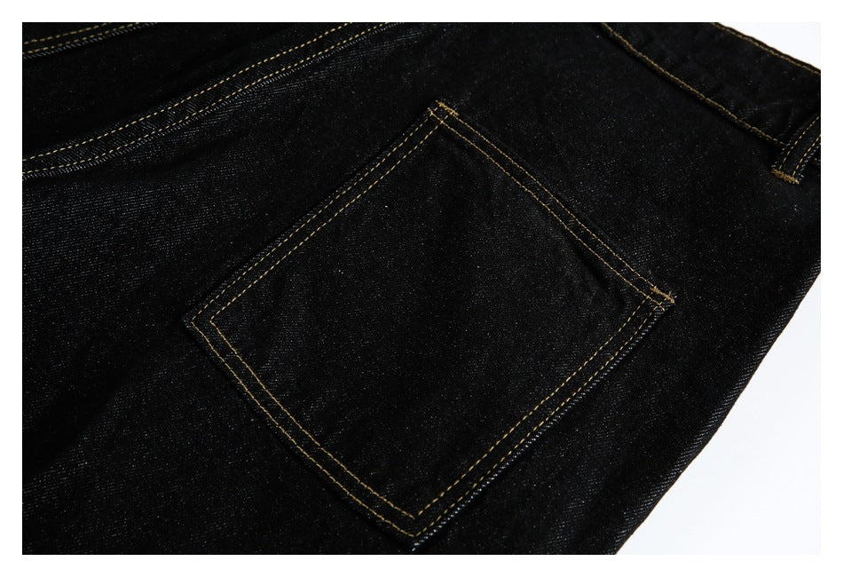 Back pocket detail on black jeans, outlined with double rows of golden stitching.