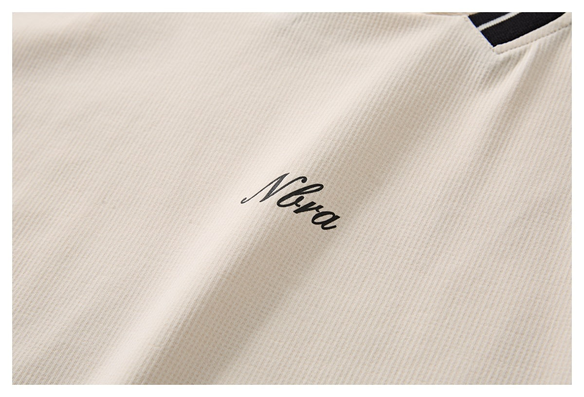 Close-up of cream ribbed fabric with a small black cursive logo print.