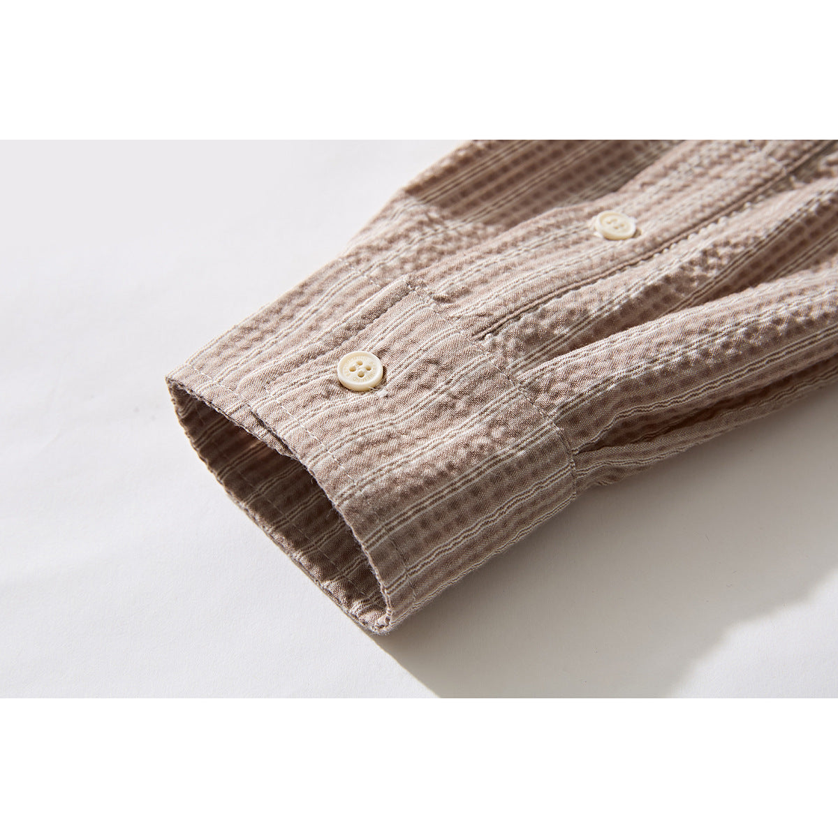 Close-up of a beige-brown patterned shirt sleeve cuff with buttons.