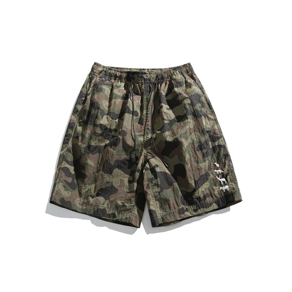 Green, brown and black camouflage shorts with drawstring, elastic waist and small white animal motif, flat front view