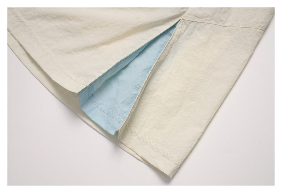 Close-up of a side slit in the cream skirt, showing pale blue inner fabric and stitching.