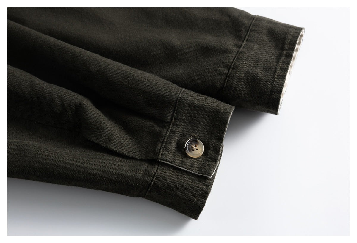 Close-up of two dark olive jacket sleeve cuffs, one fastened with a brown button.