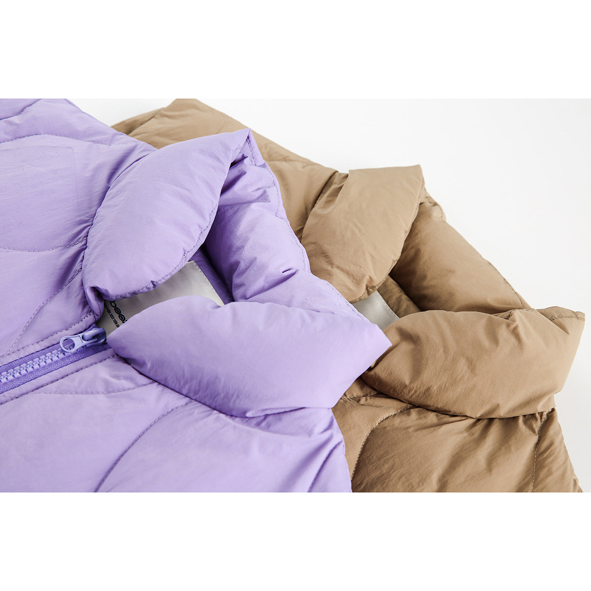 Close-up of lavender and tan quilted vest collars and padded panels, with a lavender front zipper.
