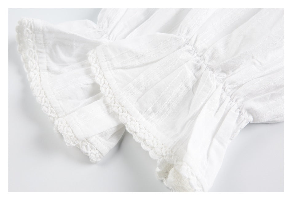 Close-up of gathered white garment fabric and sleeves with crocheted trim along the edges.