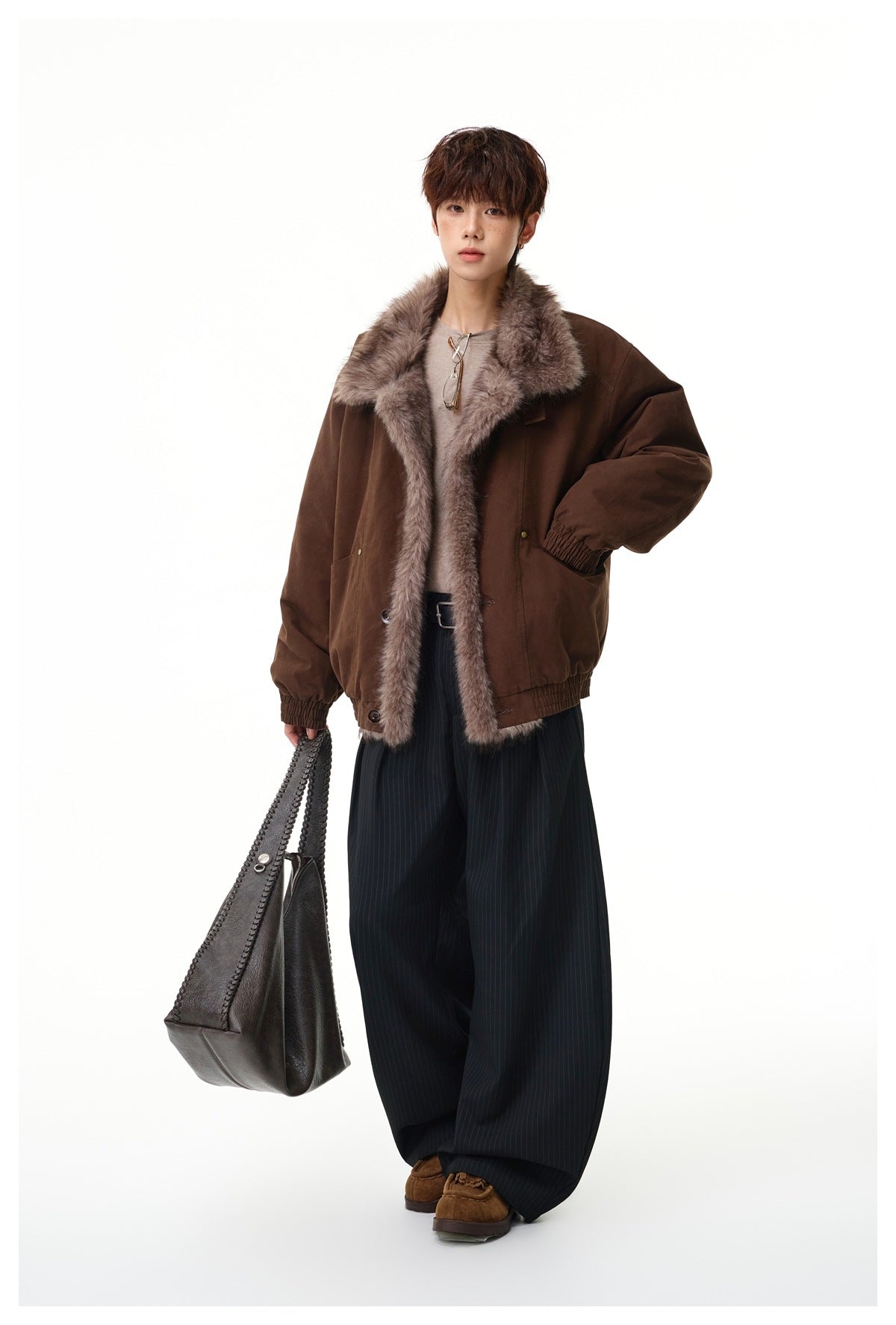 Model wearing a dark brown jacket with a wide taupe fur-trimmed collar and front, styled with pinstripe trousers.