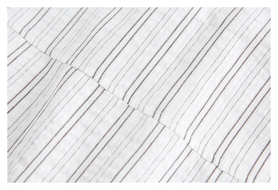 Close-up of a stitched seam joining panels of white fabric with fine dark stripes.