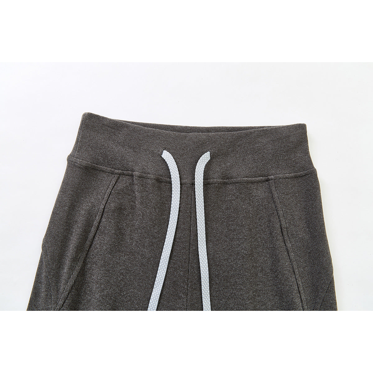 Close-up of charcoal gray pants front with a wide waistband, white drawstrings, and angled side pockets.