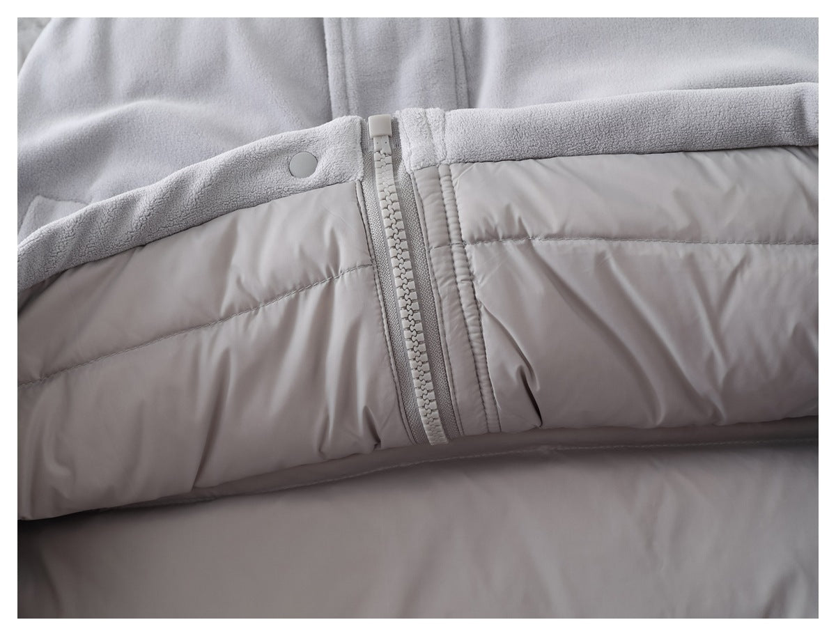 Close-up of a zipper and snap detail between pale gray fleece and quilted fabric.