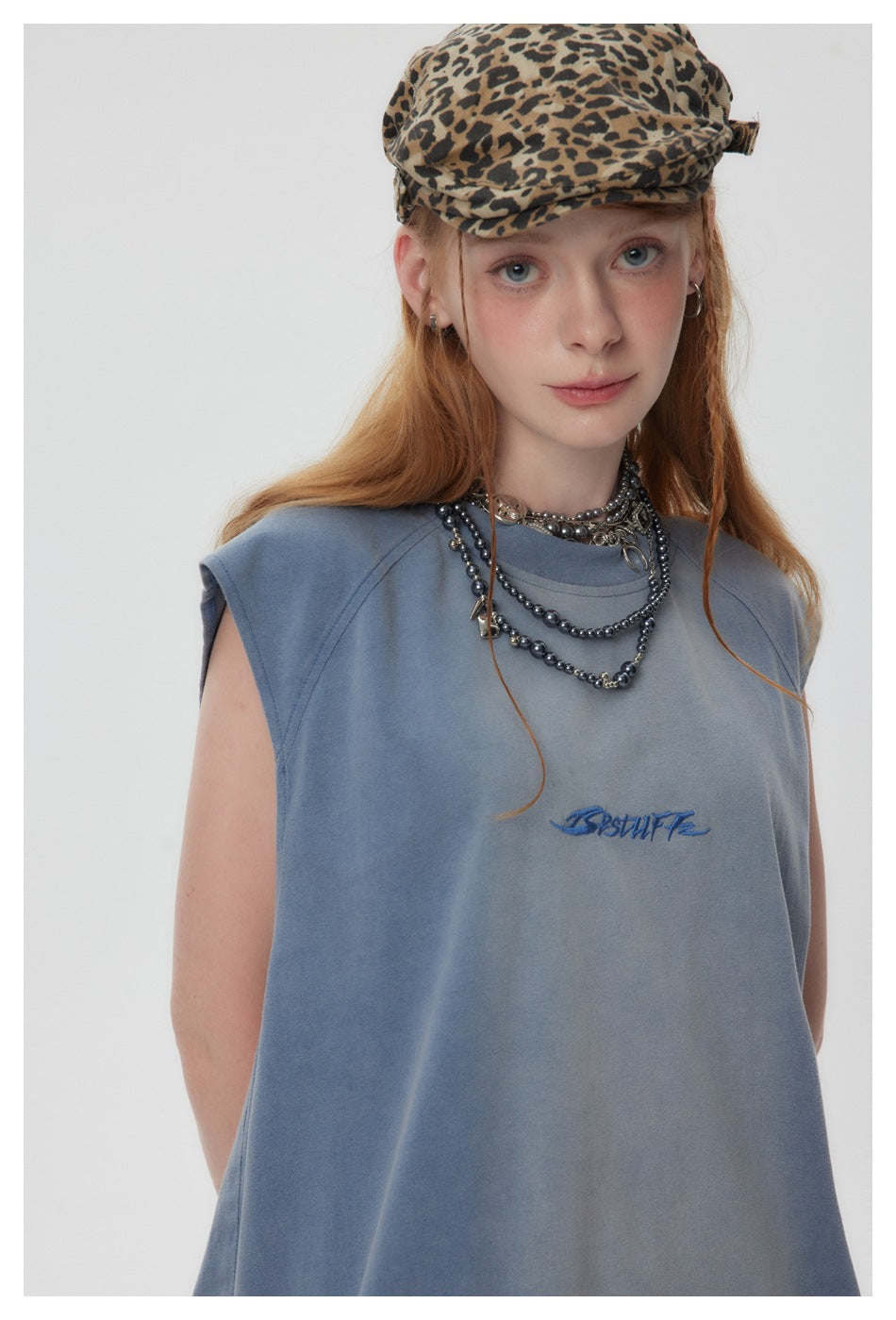 Close front view of a model wearing a faded blue sleeveless shirt with small blue script on the chest.
