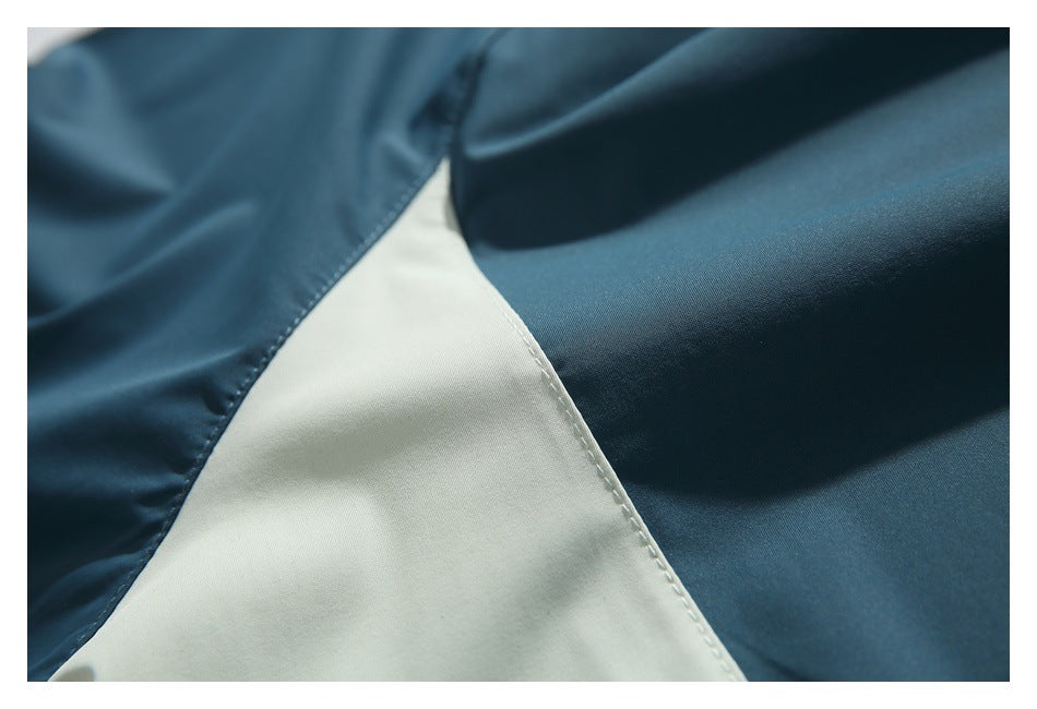 Close-up of a stitched seam joining dark teal fabric to an ivory panel.