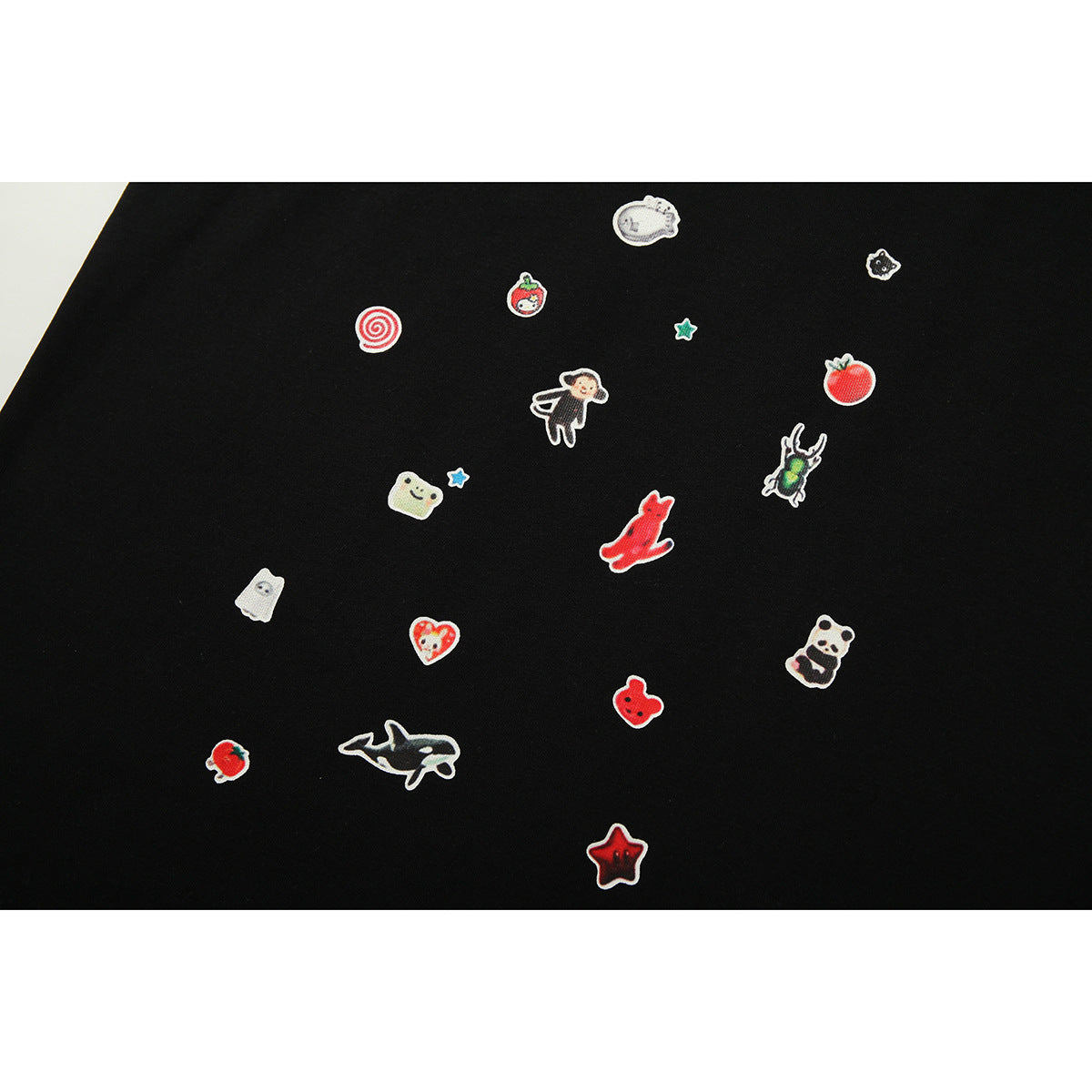 Close-up of small colorful character and object motifs scattered across black T-shirt fabric.