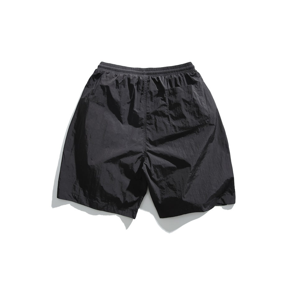Rear view of black shorts with an elastic waistband and a single patch pocket.