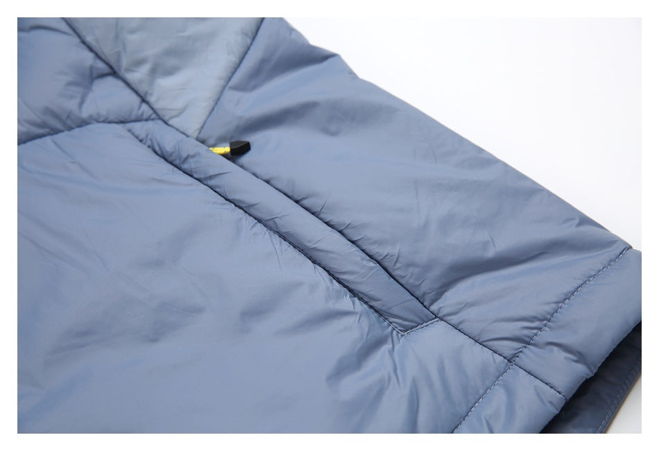 Close-up of a blue-gray quilted jacket panel with stitched seams and a small yellow-and-black zipper pull.