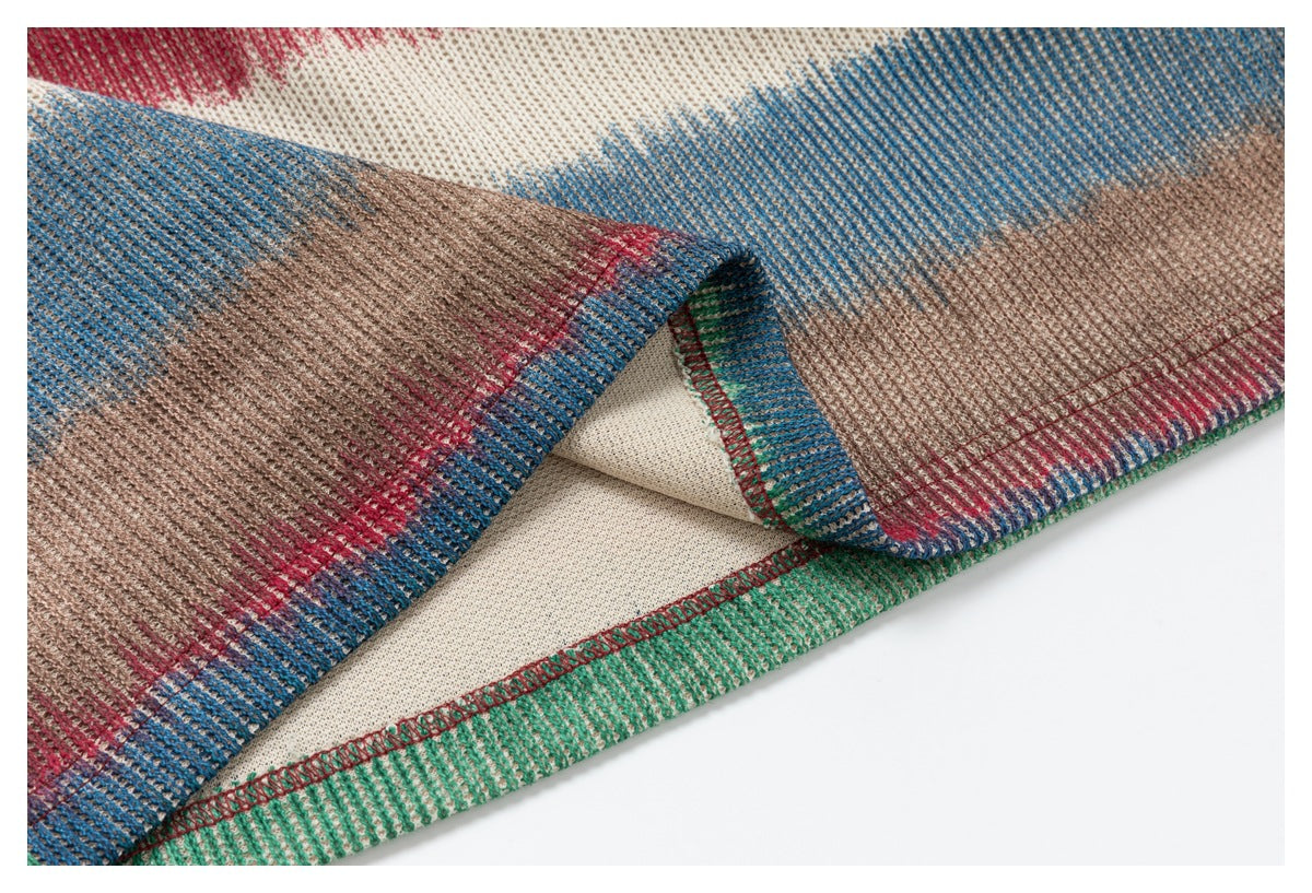 Close-up of the multicolored knit hem turned back to show the cream underside and overlocked seam.