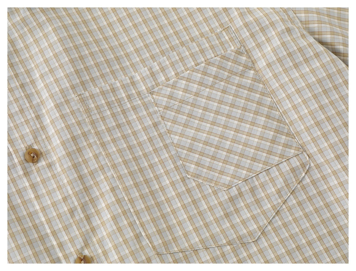 Close-up of a chest pocket and tan buttons on the cream shirt with a tan and gray check pattern.