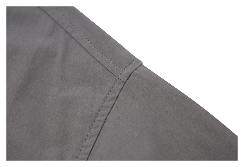 Close-up of a diagonal stitched shoulder seam on gray shirt fabric.