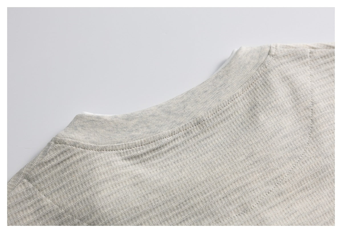 Close-up of a light heather-gray knit garment neckline with ribbed trim and visible stitching.