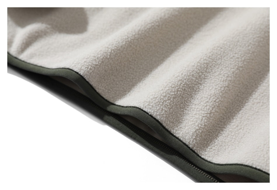 Close-up of the cream sherpa jacket hem with dark green edging and zipper.