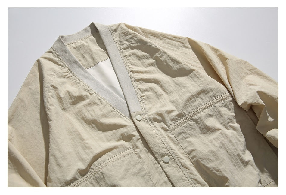 Close-up of the beige jacket’s V-neck snap front, ribbed trim, and gathered long sleeves.