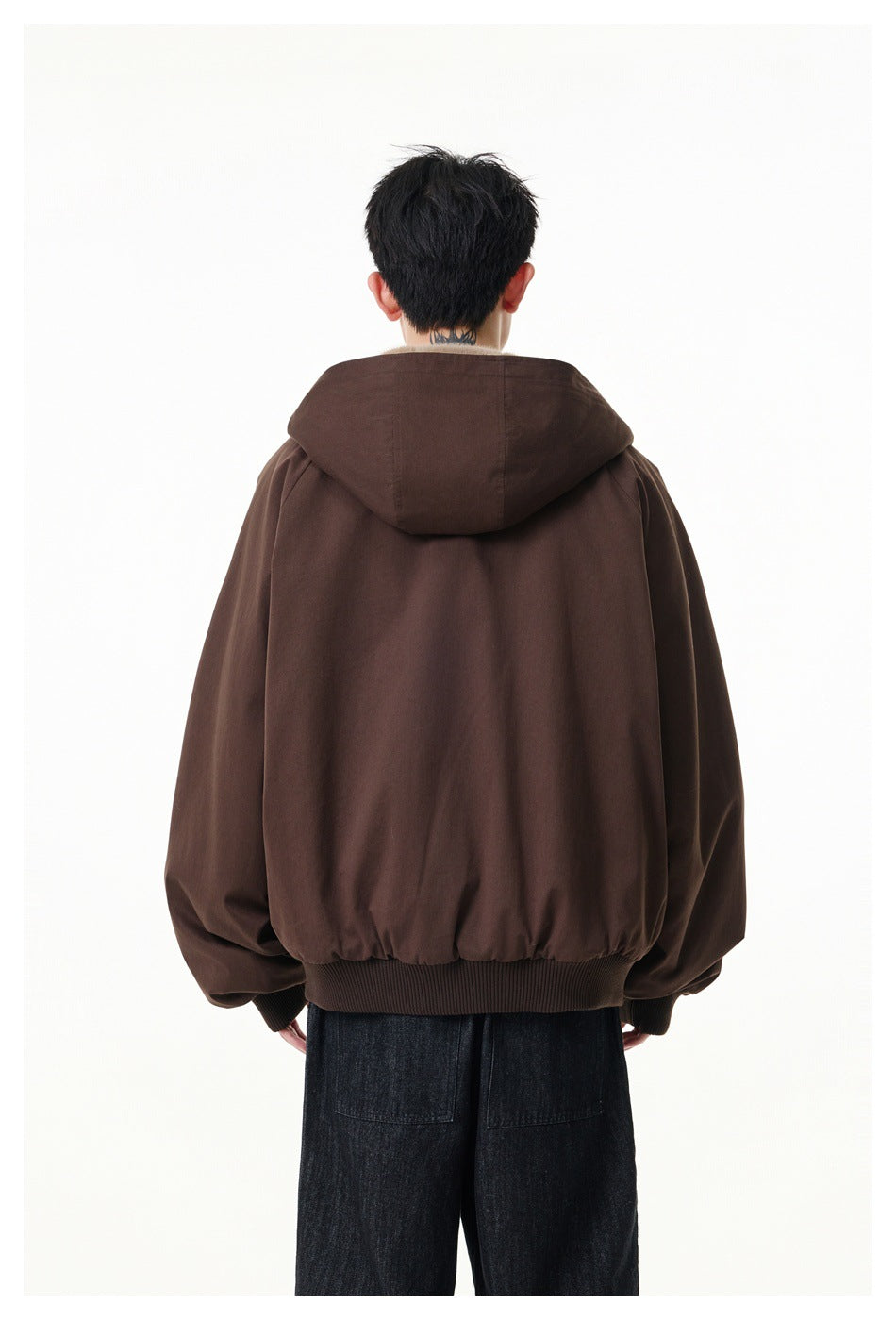 Rear view of a model wearing a dark brown hooded jacket with gathered sleeves and a ribbed hem.
