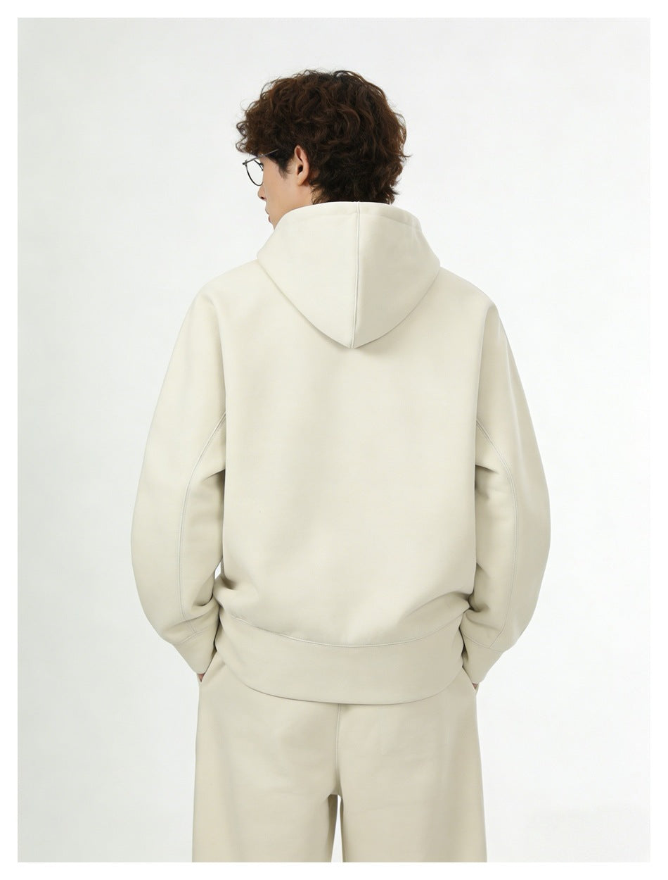 Back view of a model wearing a cream hooded sweatshirt and matching pants.