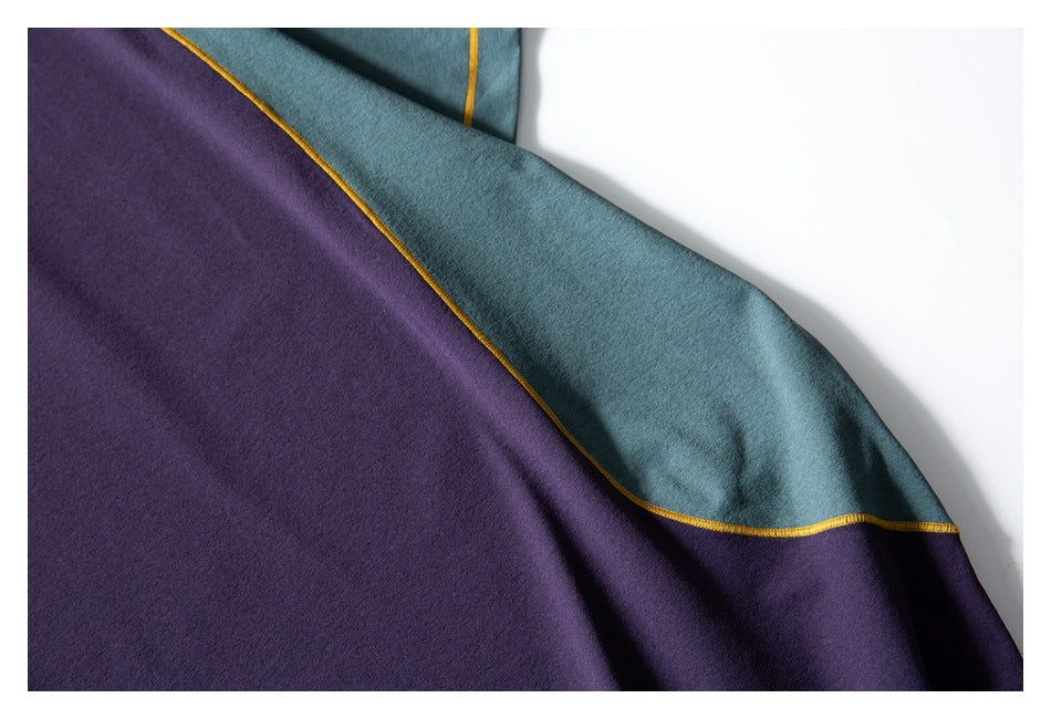 Close-up of the garment's teal and purple color-blocked panels with mustard-yellow seam stitching.